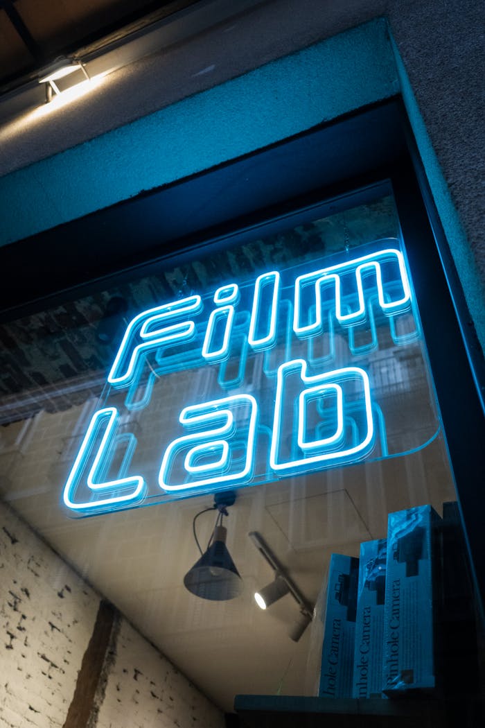 Vibrant blue neon sign for a film lab shop, captured at night with reflections.